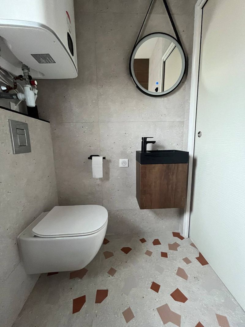 Salle d'eau avec miroir rond et WC suspendu
